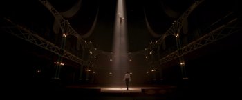 Movie still from “The Greatest Showman” (2017), directed by Michael Gracey – A man standing on a stage in front of a man hanging from a beam; Extreme Wide shot, Low angle