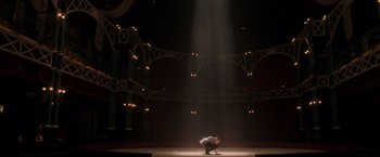 Movie still from “The Greatest Showman” (2017), directed by Michael Gracey – A man standing on one foot on a stage under a beam of light; Extreme Wide shot, Low angle