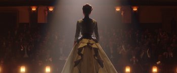 A woman standing in front of an audience wearing a dress