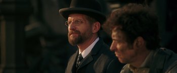 Movie still from “The Greatest Showman” (2017), directed by Michael Gracey – A man with a beard wearing a suit and a hat; Close Up shot, Over the shoulder angle