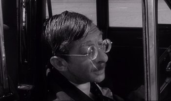 Movie still from “Cul-de-sac” (1966), directed by Roman Polanski – A black and white photo of a man wearing glasses; Close Up shot, High angle