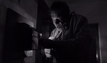 Movie still from “Cul-de-sac” (1966), directed by Roman Polanski – An old man is looking at a piece of paper in the dark; Close Up shot, Low angle