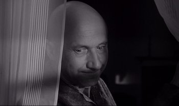 Movie still from “Cul-de-sac” (1966), directed by Roman Polanski – A man with a bald head is looking out a window; Close Up shot, Low angle