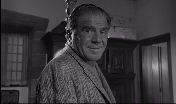 Movie still from “Cul-de-sac” (1966), directed by Roman Polanski – An older man in a robe is smiling for the camera; Close Up shot, Low angle