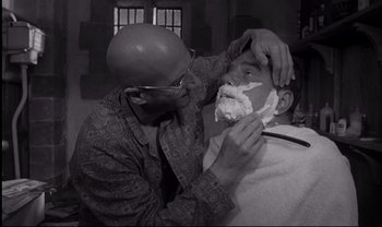 Movie still from “Cul-de-sac” (1966), directed by Roman Polanski – A man shaving another man's face with a razor; Close Up shot, Over the shoulder angle