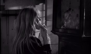 Movie still from “Cul-de-sac” (1966), directed by Roman Polanski – A woman holding a bag in front of a mirror; Close Up shot, Over the shoulder angle