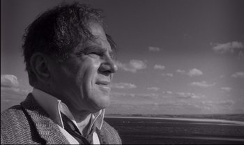 Movie still from “Cul-de-sac” (1966), directed by Roman Polanski – Black and white photograph of a man looking out at the ocean; Close Up shot, Low angle