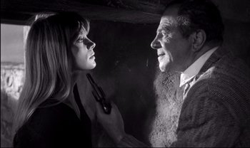 Movie still from “Cul-de-sac” (1966), directed by Roman Polanski – An older man and a younger woman are looking at each other; Close Up shot, High angle