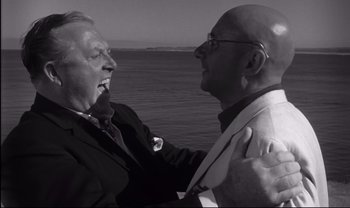 Movie still from “Cul-de-sac” (1966), directed by Roman Polanski – Two men in suits and ties near a body of water; Close Up shot, Low angle
