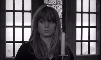Movie still from “Cul-de-sac” (1966), directed by Roman Polanski – A black and white photo of a woman holding a candle; Close Up shot, Over the shoulder angle