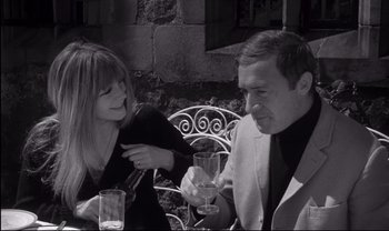 Movie still from “Cul-de-sac” (1966), directed by Roman Polanski – A man and a woman sitting at an outdoor table; Medium shot, High angle