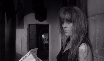Movie still from “Cul-de-sac” (1966), directed by Roman Polanski – A woman with long hair holding a newspaper; Close Up shot, Low angle