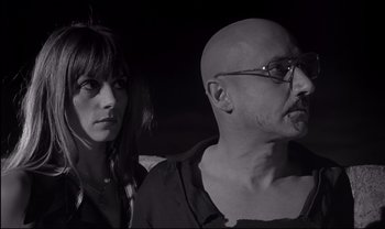 Movie still from “Cul-de-sac” (1966), directed by Roman Polanski – A man and a woman standing next to each other in front of a dark background; Close Up shot, Low angle