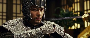 Movie still from “Curse of the Golden Flower” (2006), directed by Yimou Zhang – A person wearing armor and holding a sword; Close Up shot, Over the shoulder angle