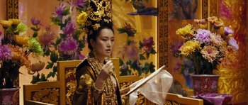 Movie still from “Curse of the Golden Flower” (2006), directed by Yimou Zhang – A woman dressed in oriental clothing holding an open book; Medium shot, Over the shoulder angle