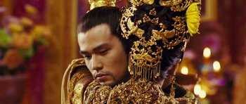 Movie still from “Curse of the Golden Flower” (2006), directed by Yimou Zhang – A man in a gold costume with a crown on his head; Close Up shot, Over the shoulder angle