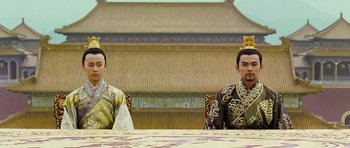 Movie still from “Curse of the Golden Flower” (2006), directed by Yimou Zhang – Two men sitting at a table in front of a building; Medium shot, Low angle
