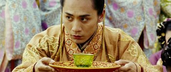 Movie still from “Curse of the Golden Flower” (2006), directed by Yimou Zhang – A man holding a plate with a bowl on top of it; Close Up shot, Low angle