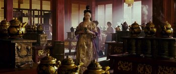 Movie still from “Curse of the Golden Flower” (2006), directed by Yimou Zhang – A woman in oriental dress looking at her cell phone; Medium shot, Over the shoulder angle