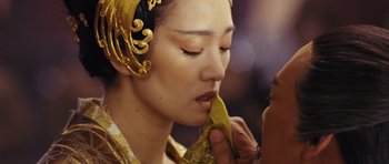 Movie still from “Curse of the Golden Flower” (2006), directed by Yimou Zhang – A woman is holding a banana in front of her face; Close Up shot, Over the shoulder angle