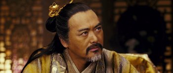 Movie still from “Curse of the Golden Flower” (2006), directed by Yimou Zhang – A man with long black hair wearing a gold robe; Close Up shot, Over the shoulder angle