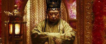 Movie still from “Curse of the Golden Flower” (2006), directed by Yimou Zhang – An older man wearing a green robe and a black hat; Close Up shot, High angle