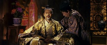 Movie still from “Curse of the Golden Flower” (2006), directed by Yimou Zhang – Two men dressed in traditional chinese garb reading a book; Medium shot, Over the shoulder angle