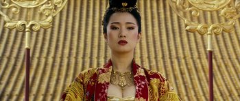 Movie still from “Curse of the Golden Flower” (2006), directed by Yimou Zhang – A woman in a gold and red dress with a gold necklace; Close Up shot, Low angle