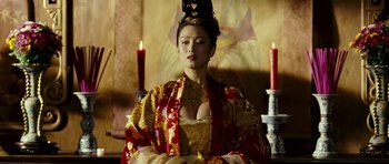 Movie still from “Curse of the Golden Flower” (2006), directed by Yimou Zhang – A woman in a red and gold dress with candles in front of a painting; Medium shot, Low angle