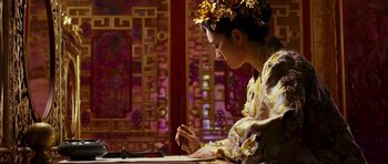 Movie still from “Curse of the Golden Flower” (2006), directed by Yimou Zhang – A woman is writing on a piece of paper; Medium shot, Low angle