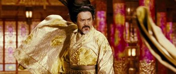 Movie still from “Curse of the Golden Flower” (2006), directed by Yimou Zhang – A man in a gold and black costume with long black hair; Medium shot, Low angle