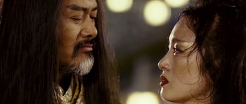 Movie still from “Curse of the Golden Flower” (2006), directed by Yimou Zhang – A man and a woman face to face in front of lights; Close Up shot, Low angle