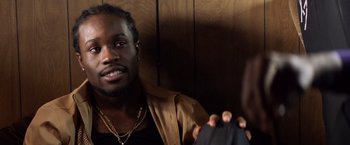 Movie still from “Cut Throat City” (2020), directed by RZA – A man in a brown jacket is taking a picture of himself; Close Up shot, Over the shoulder angle