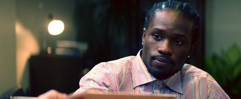 Movie still from “Cut Throat City” (2020), directed by RZA – A person sitting at a table; Close Up shot, High angle