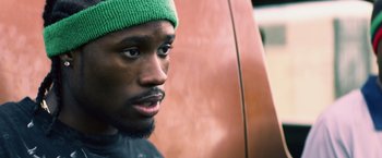 Movie still from “Cut Throat City” (2020), directed by RZA – A person wearing a green hat; Close Up shot, Over the shoulder angle