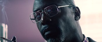 Movie still from “Cut Throat City” (2020), directed by RZA – A person wearing glasses; Close Up shot, Low angle