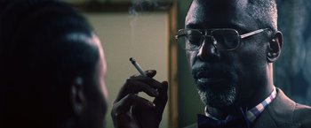 Movie still from “Cut Throat City” (2020), directed by RZA – A man smoking a cigarette in front of a mirror; Close Up shot, Over the shoulder angle