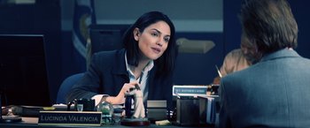 Movie still from “Cut Throat City” (2020), directed by RZA – A woman sitting at a desk in front of some books; Medium shot, Over the shoulder angle