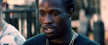 Movie still from “Cut Throat City” (2020), directed by RZA – A person wearing a black t - shirt; Close Up shot, Over the shoulder angle