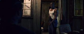 Movie still from “Cut Throat City” (2020), directed by RZA – A man standing in front of a window holding a towel; Medium shot, Over the shoulder angle