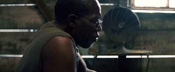 Movie still from “Cut Throat City” (2020), directed by RZA – A person wearing glasses and looking to the side; Close Up shot, Low angle