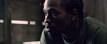 Movie still from “Cut Throat City” (2020), directed by RZA – A person wearing a green shirt; Close Up shot, Low angle