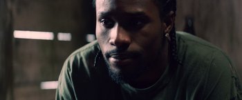 Movie still from “Cut Throat City” (2020), directed by RZA – A person wearing a green shirt; Close Up shot, Low angle