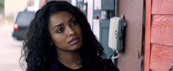 Movie still from “Cut Throat City” (2020), directed by RZA – A woman with long black curly hair is looking at the camera; Close Up shot, Over the shoulder angle