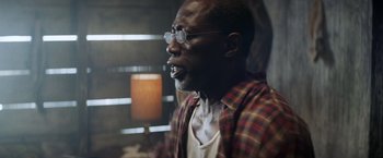 Movie still from “Cut Throat City” (2020), directed by RZA – An older man wearing glasses and a plaid shirt; Close Up shot, Low angle