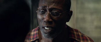 Movie still from “Cut Throat City” (2020), directed by RZA – An older man wearing glasses and a plaid shirt; Close Up shot, Over the shoulder angle