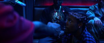 Movie still from “Cut Throat City” (2020), directed by RZA – A person sitting in a room with a person holding a cell phone in his hand; Close Up shot, Over the shoulder angle