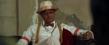 Movie still from “Cut Throat City” (2020), directed by RZA – A man wearing a hat and a bow tie; Close Up shot, Low angle