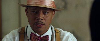 Movie still from “Cut Throat City” (2020), directed by RZA – A person wearing a hat and a bow tie; Close Up shot, Low angle
