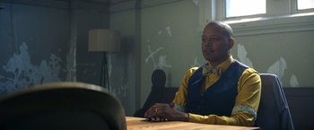 Movie still from “Cut Throat City” (2020), directed by RZA – A man sitting at a table in front of a lamp; Close Up shot, Over the shoulder angle